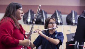 music educator helping student playing the flute