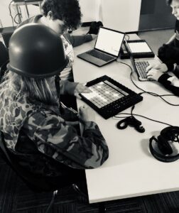 students in NVAA Music Tech program sitting around desk and working at DAWs