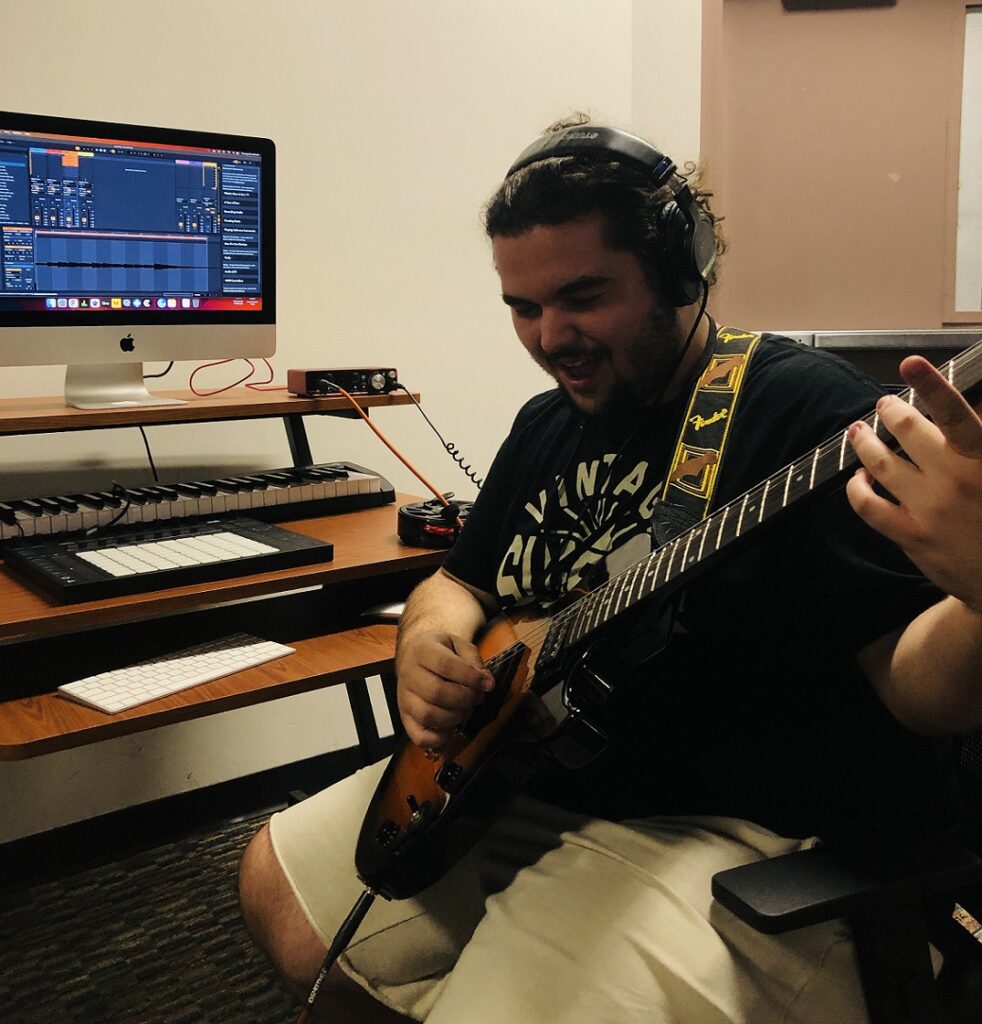 student playing guitar while sitting at DAW