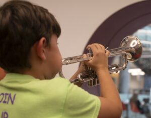 child exploring the trumpet at the Instrument Petting Zoo during Meet the Opera workshop