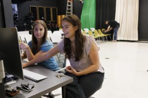 two women sitting in front of computer