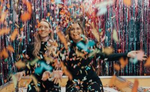 two women celebrating with streamers and confetti all around them