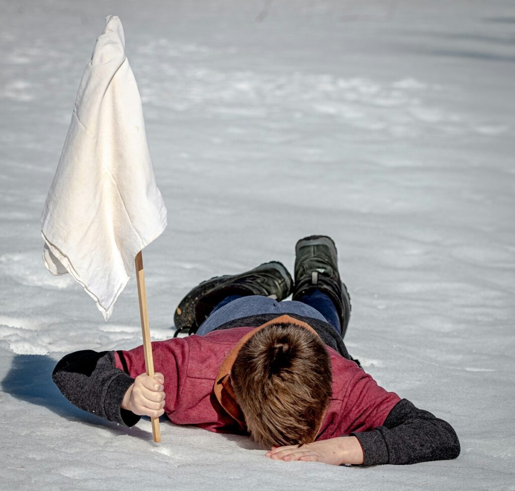 child face down on ground holding a white flag