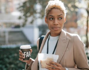 woman walking holding coffee cup and sandwich