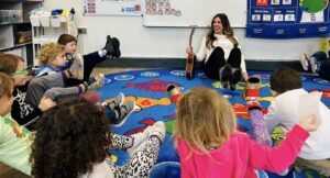 Dr. Cassandra Eisenreich holding her legs up in a circle with preschoolers 