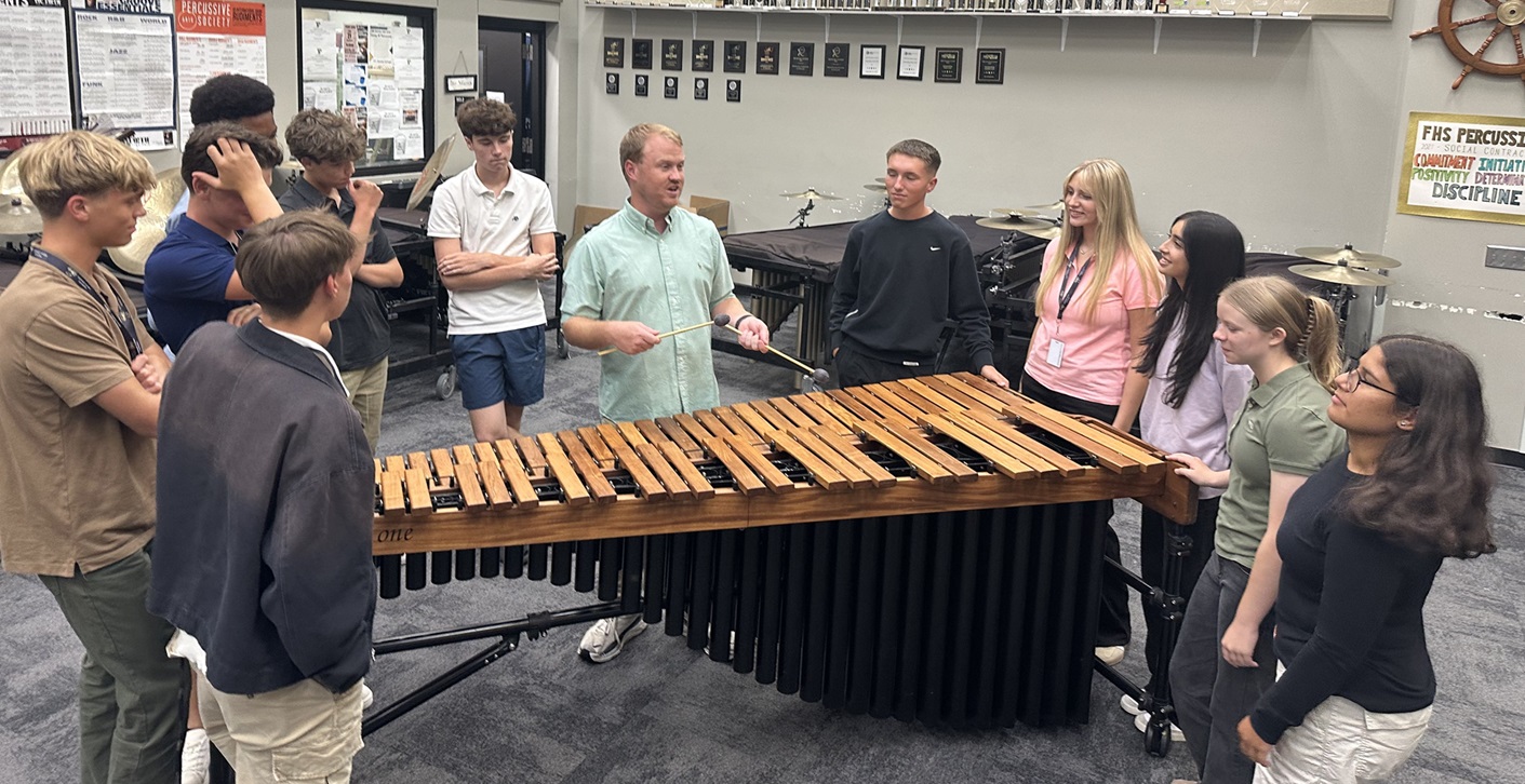 percussion teacher showing how to play the marimba to a group of students 