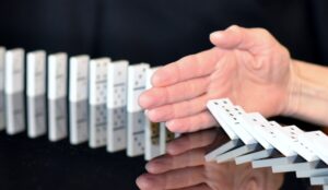 hand blocking falling dominoes