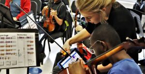 Annie Ray showing Crescendo Orchestra student instruction on a tablet