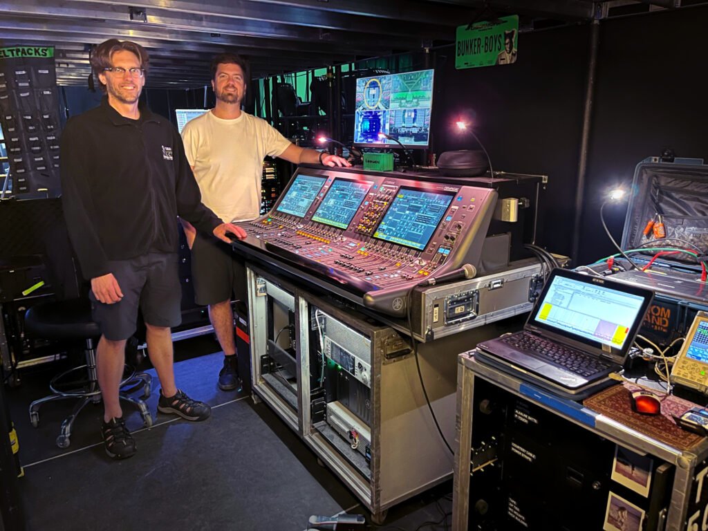 two men standing next to audio mixer