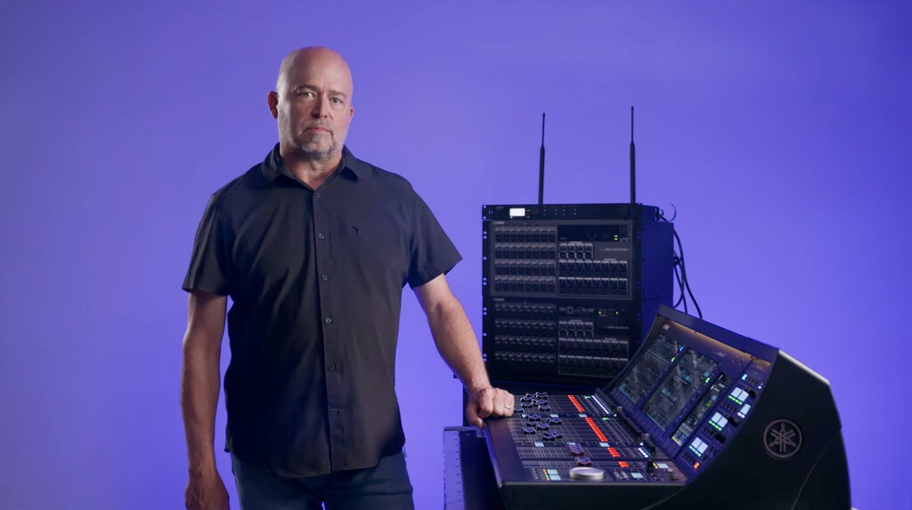 man posing for photo next to audio mixer