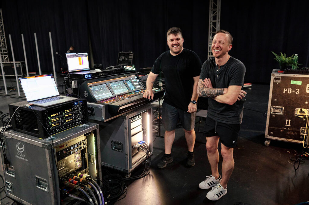 two men standing in front of audio mixer