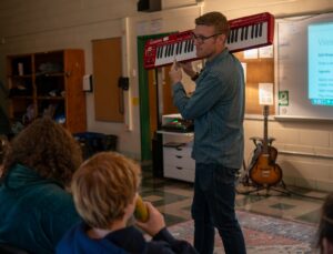 Bob Habersat holding keyboard in front of choir room