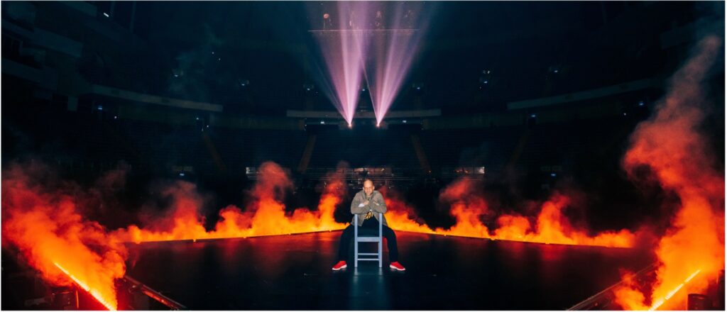 man sitting on stage surrounded by fire