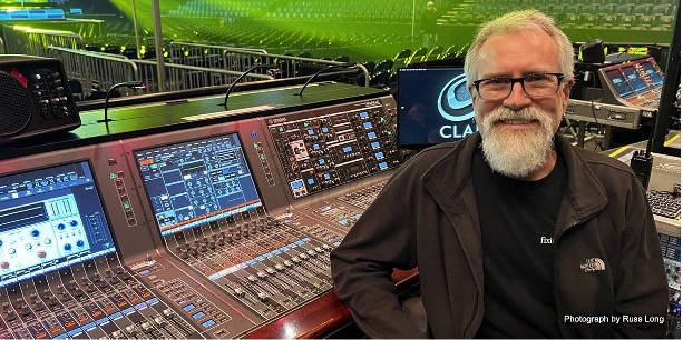 man smiling in front of an audio mixer