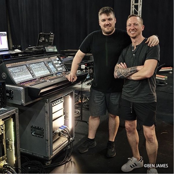 two men standing next to an audio mixer