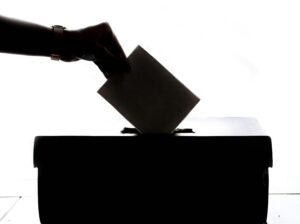 silhouette of someone placing ballot in a box