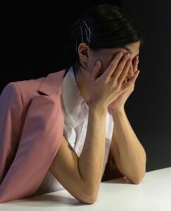 exhausted woman holding face in hands