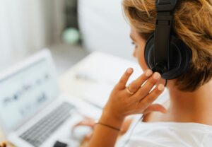 woman with open laptop and wearing headphones