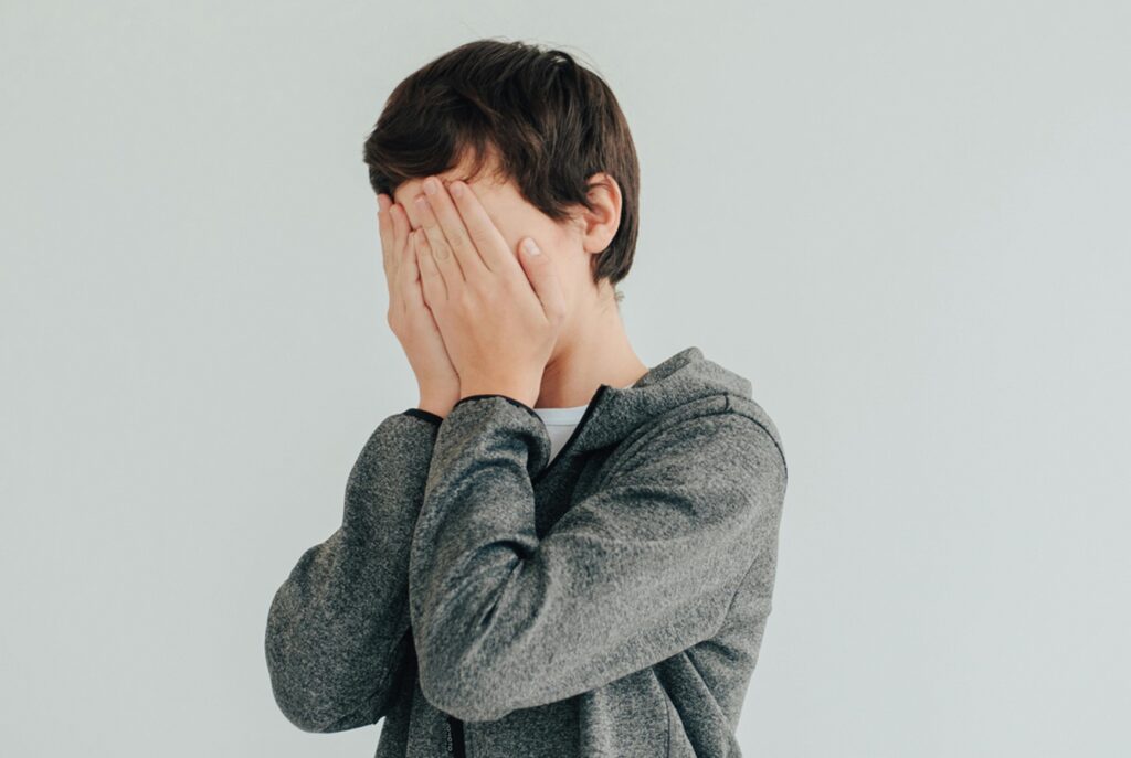 teen with face in hands in panic