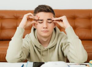 stressed out student with hands by his eyes