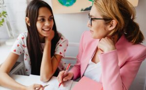 student and teacher sitting side by side and smiling