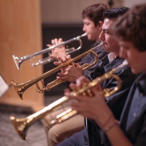 three students playing trumpet 