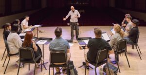 man presenting a workshop to small group sitting in a semi circle in front of him