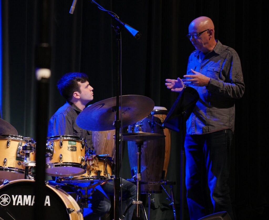 man standing and talking to a drummer