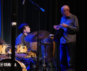 man standing and talking to a drummer