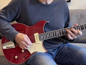 A seated guitarist bending a string on an electric guitar.