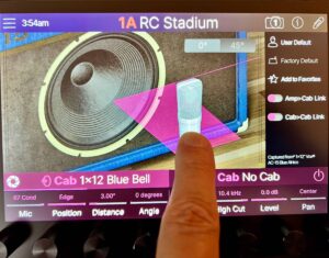 A finger touching a touchscreen on a guitar effects processor to change the microphone model positioned in front of an image of a speaker.