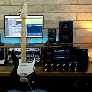 A green solid-body electric guitar next to an effects processor.