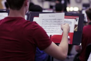 music student pulling out sheet music from folder on music stand