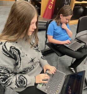 two students working on laptops
