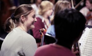 violin students smiling during rehearsal