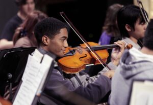 student playing violin during rehearsal