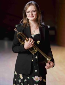 A young woman holding a trumpet.
