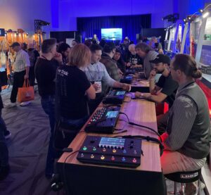 A group of people trying out effects processors at a trade show.