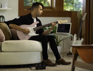 male playing Yamaha Pacifica guitar while sitting on couch 