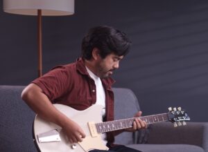 male playing the Yamaha Revstar while sitting on a couch