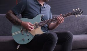someone playing Yamaha Revstar guitar while sitting on couch 