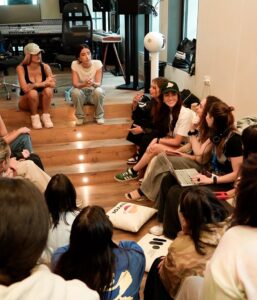 two women sitting on a stair talking to a group of women