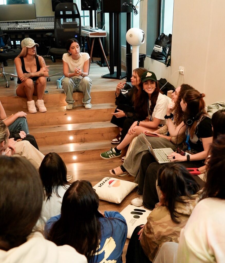 two women sitting on a stair talking to a group of women