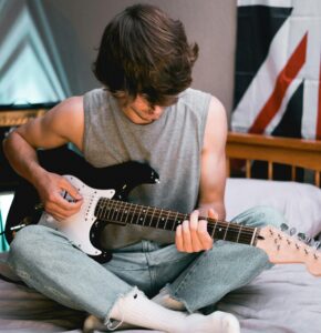 guitarist playing while sitting on bed