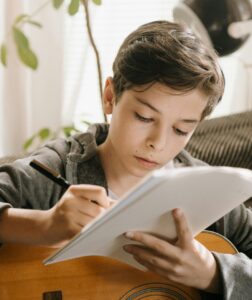 student writing songs while holding guitar