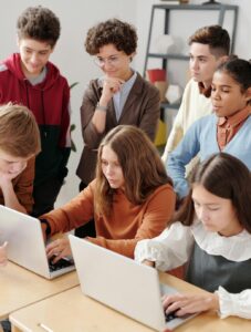 teacher and students looking at computer laptops