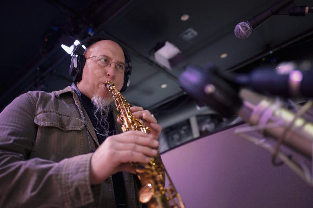 man playing soprano saxophone in a studio