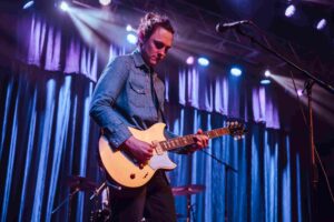 A man playing an electric guitar onstage.