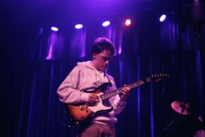 A man playing an electric guitar onstage.