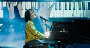 A man playing an acoustic piano onstage.